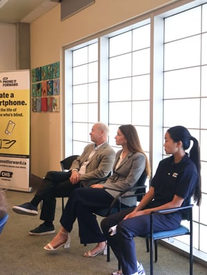 Three people sit in chairs near a window during the Phone It Forward event.